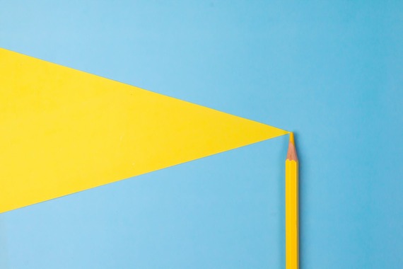 yellow colored pencil pointing a cone of light onto a blue background