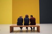 three adults sitting on a bench in a museum