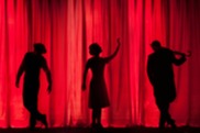 silhouette of actors against red curtain