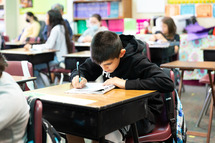 Boy working on paper leaning closely to desk