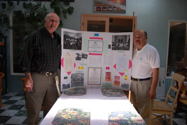Two men standing next to a project board 
