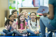 School children and a teacher reading a book