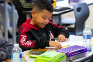 Boy reading paper at a school desk