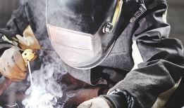 Person welding in protective helmet and gloves