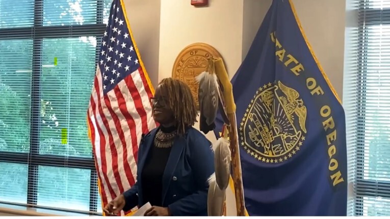 A person standing indoors between two flags