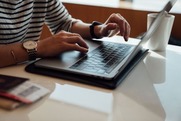 Person sitting at a desk typing on a laptop 