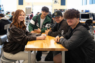 Girl and three boys at a desk smiling