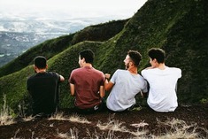 Row of four men sitting on a mountain