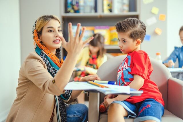 A teacher showing a child numbers with her hand