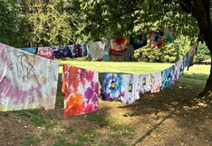 Camp-Starlight tie dye tees hanging to dry in grassy shade