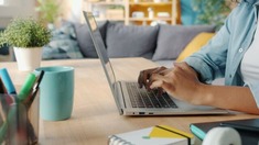 Person typing on a laptop on a wooden desk.
