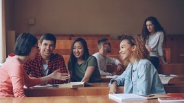 Group of students talking and laughing in a lecture hall.