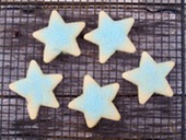 five sugar cookies shaped like stars with blue sprinkles