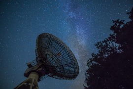 weather satellite in a field below starry night sky