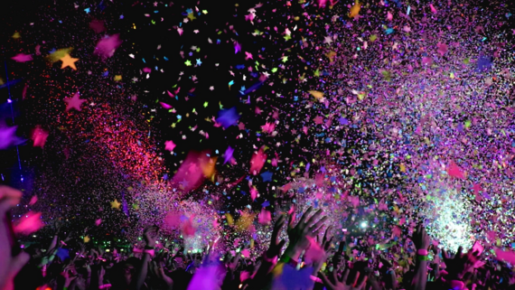 dark background with many hands waving and pink confetti