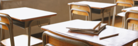 a row of desks and a stack of notebooks on top of a desk