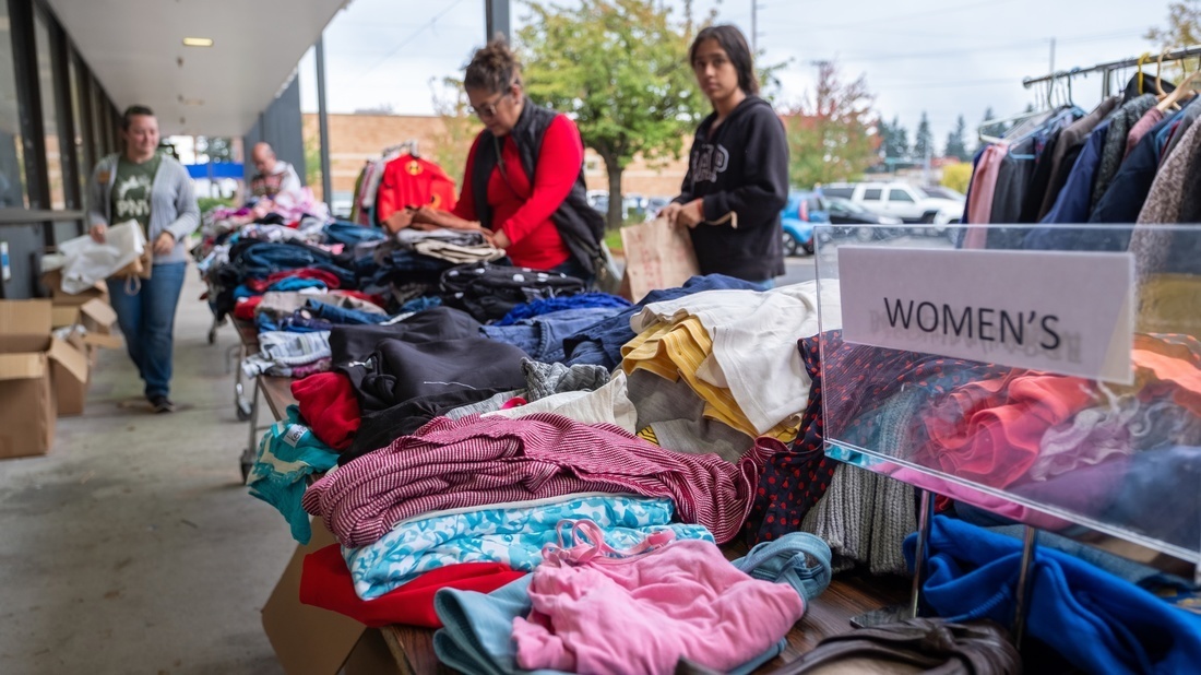 Table full of clothing with two people shopping