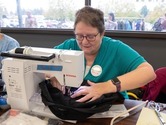 A woman sewing black fabric with a sewing machine