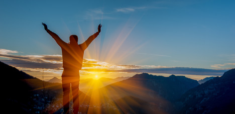 photo of person looking out over the mountains at a sunset