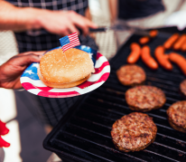 photo of a grill with burgers and hot dogs cooking
