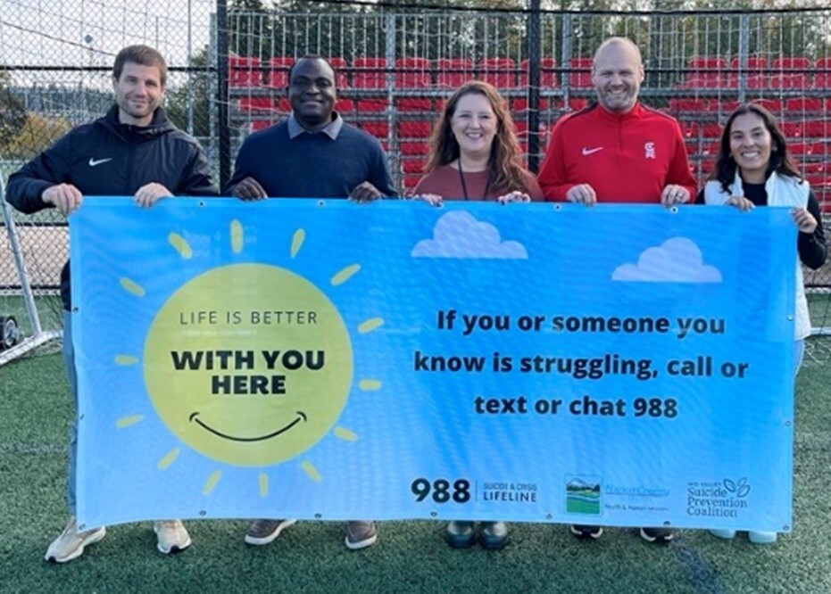 People from Capital Fútbol Club and Marion County hold up an English 988 banner