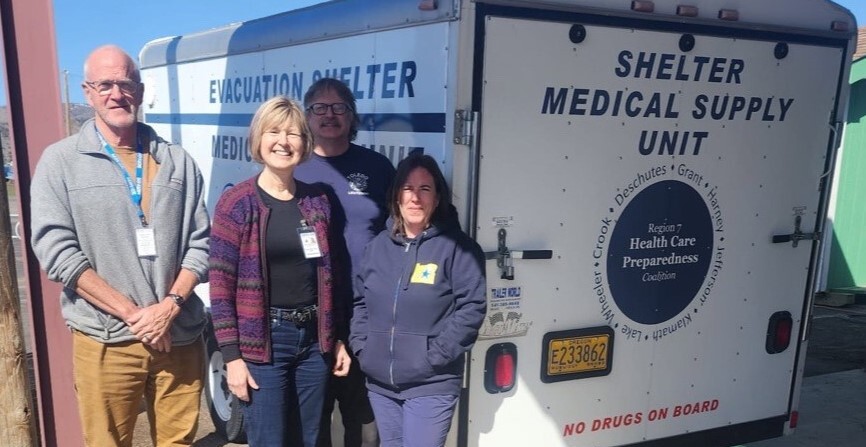 a group of four people standing in front of a van that says Shelter Medical Supply Unit