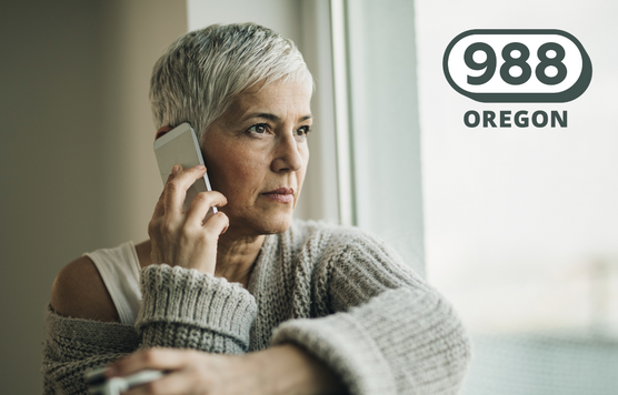 photo of a middle-aged woman looking pensive and on the phone, looking out a window