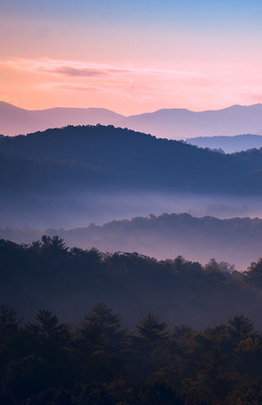 View of mountain ridge with pink and purple dawn sky above