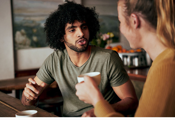 Man and woman engaged in meaningful conversation seated at counter of coffee shop
