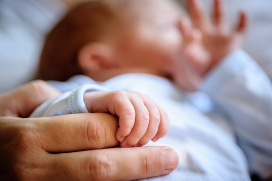 Close up photo of adult hand cradling infant hand