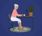 A woman with gray hair sitting in front of a computer at a desk.