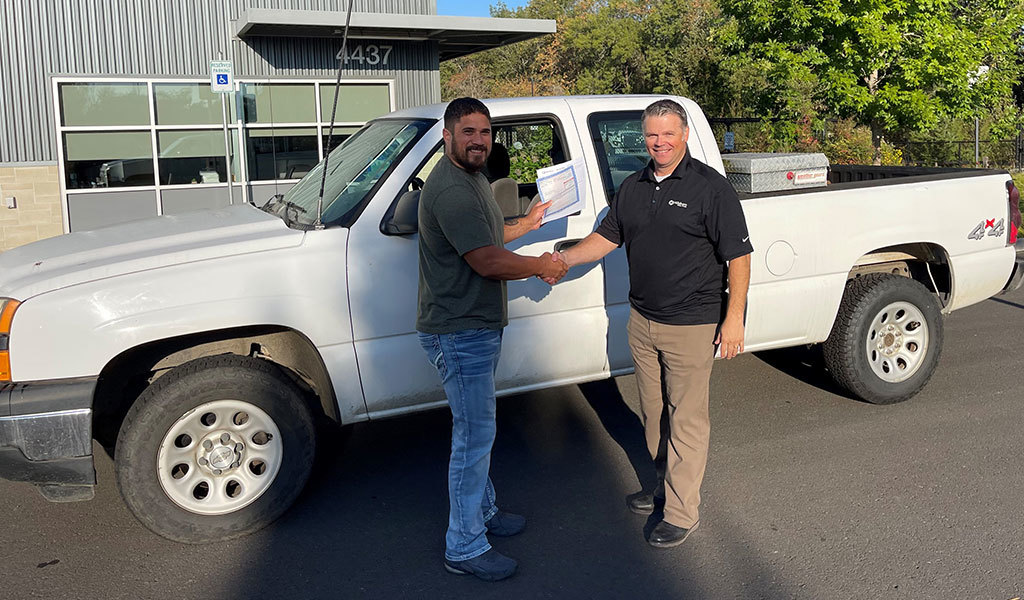 Jeremy Toevs shakes hands with City of Hillsboro Fleet Superintendent Donny Leader in front of the donated pickup truck