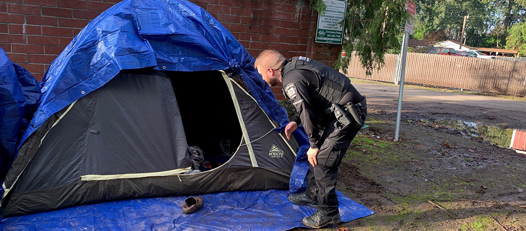 A Hillsboro Police Department Crisis Intervention Team Officer speaks to a community member in a tent