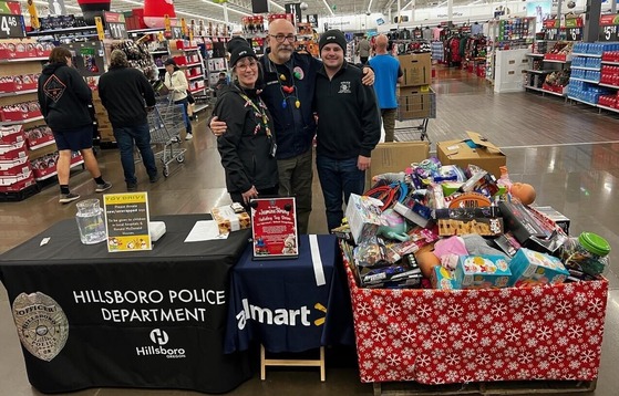 Holiday Toy Drive at Walmart - Hillsboro and Forest Grove Police employees posing next to a large bin of toys and other gifts.