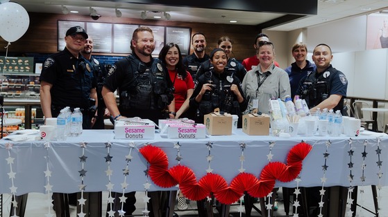 Officers and Target Staff members standing behind a table with donuts, coffee and water.