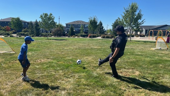 Police Officer Playing Soccer with a Child in a Park