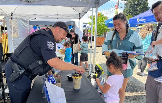 Hillsboro Police Officer Talks to a Young Girl and Her Family; Handing Her a Sticker Badge and Pencil