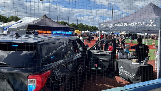 Hillsboro Police Officer talking with attendees at the Mariachi Festival - Wide View to include the tent and patrol vehicle.