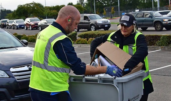 Hillsboro Police volunteer and Iron Mountain driver dumping a box of papers in a shred bin. 