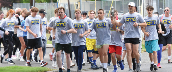 Special Olympic Athletes and an Officer Running and Holding the Torch