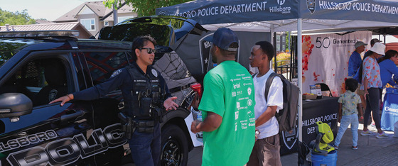 Hillsboro Police Officer Talking with Two Community Members by a Police Vehicle