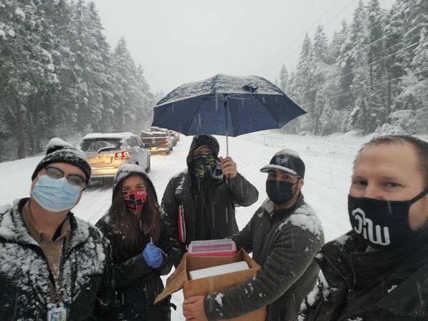 Five health workers in masks, holding equipment in the snow