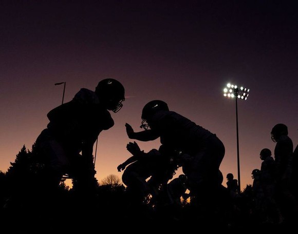 Silhouettes of football players playing as the sun is almost completely set