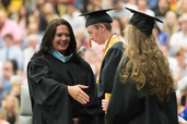 Principal offering hand shake to graduating woman in cap and gown