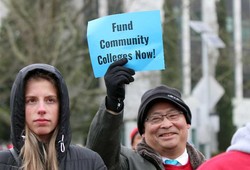 man holding "fund community colleges now" sign