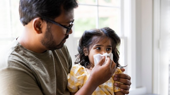 child blowing her nose into dad's tissue