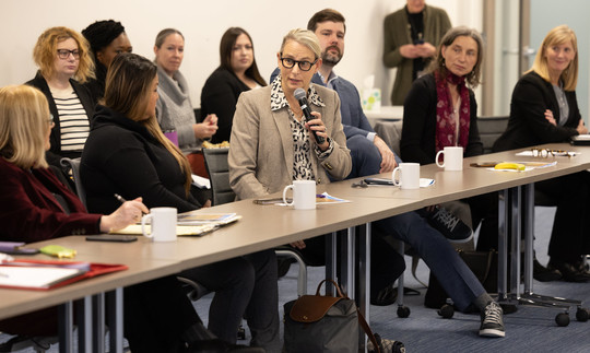 Senator Lieber holding a microphone and speaking to a group of people at the Multnomah County Legislative Breakfast