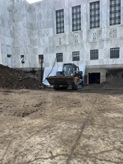 A bulldozer with scoop filled with dirt in front of the Capitol construction 