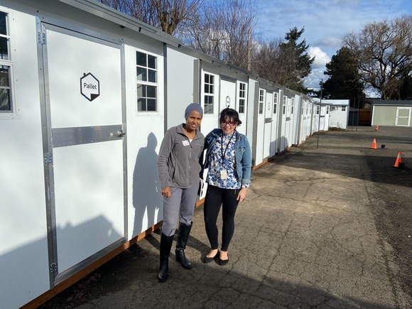 Commissioner Fai and Annie Naranjo-Rivera stand in front of new shelter pod housing units