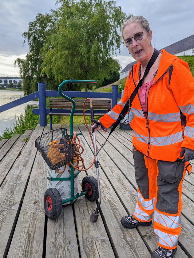 A woman holding a blow torch to handle weeds next to sensitive wildlife